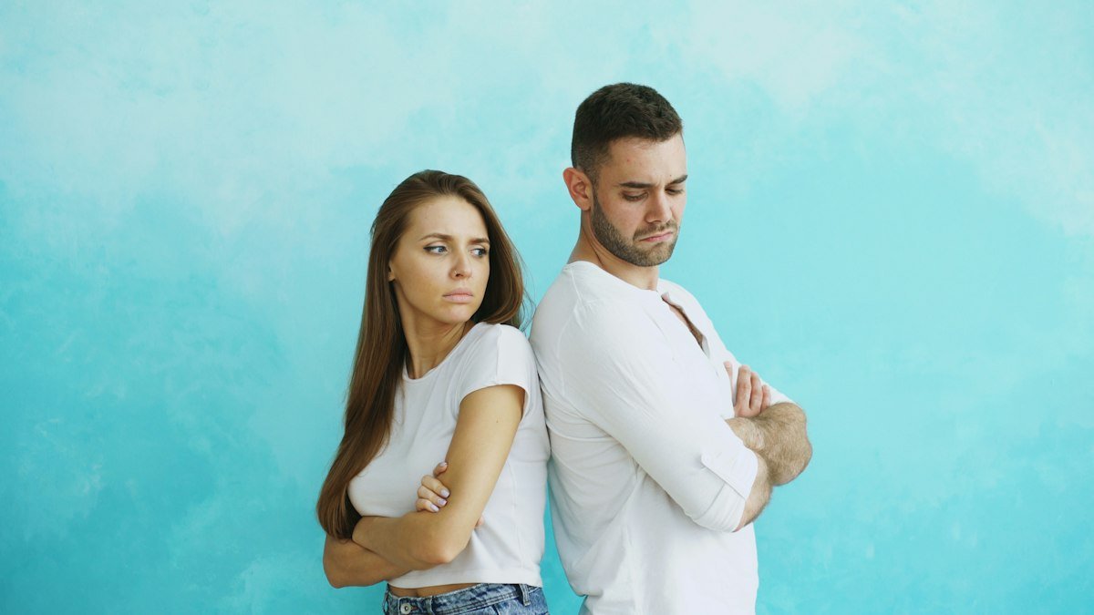 Couple standing back to back with arms crossed after an argument